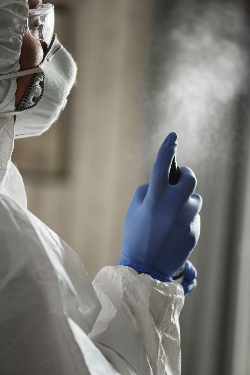 Close-up of a gloved hand spraying EPA-registered disinfectant during biohazard cleanup in Oklahoma