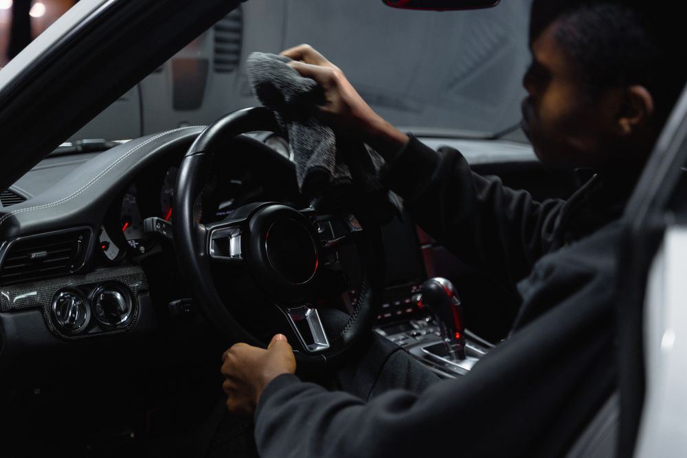 Technician wiping down a steering wheel during vehicle biohazard decontamination in Oklahoma